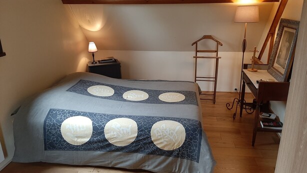 Una camera da letto con un letto, un comodino, una scrivania, una sedia e una scala.