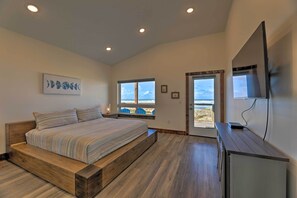 Quarto com cama de madeira, uma janela ampla com vista e televisão de tela plana sobre um armário de madeira.