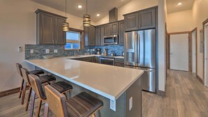 A modern kitchen with a large island, stainless steel appliances, and a stone backsplash. - Sanderling Sea Cottages, Unit 7 w/ Beach Access! (Waldport)
