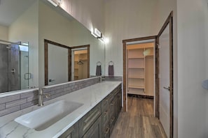 Casa de banho moderna com um espelho grande, duas pias e um closet espaçoso.