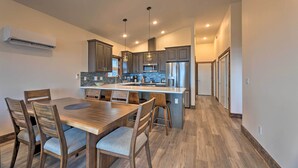 A modern kitchen with a central island, wooden dining table, and chairs. - Sanderling Sea Cottages, Unit 7 w/ Beach Access! (Waldport)