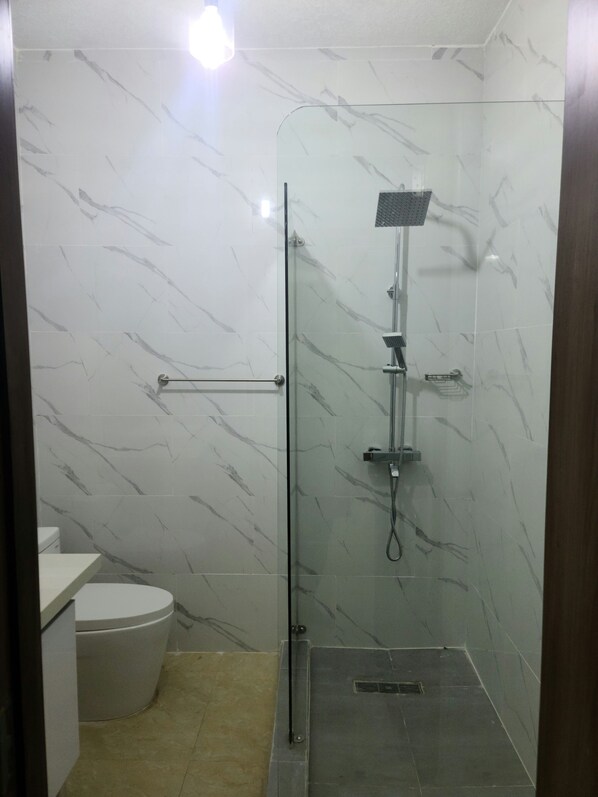Un baño con ducha acristalada, inodoro y lavamanos.