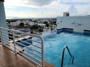 Una piscina en la azotea con vistas al paisaje urbano, incluyendo edificios y un puente distante.