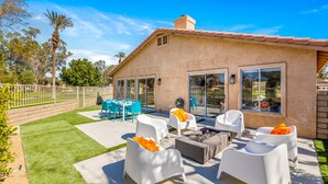 Un patio con mobiliario exterior, una chimenea y vistas al jardín trasero.