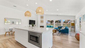 Una cocina moderna con una isla central, horno empotrado e iluminación colgante.