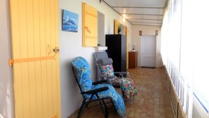 Un pasillo con piso de baldosas, una silla estampada azul, una silla gris y un mueble negro.