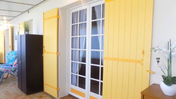 Una habitación con un gran ventanal, un armario negro y un mueble de madera con una planta.