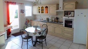 A kitchen with a dining table, chairs, cabinets, a refrigerator, and a microwave. - Saint Palais sur Mer - BEAUTIFUL SERVICES for THIS INDIVIDUAL HOUSE (ST PALAIS SUR MER)