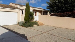 A residential property with a garage, a small front yard with a gravel path, and a tree. - Saint Palais sur Mer - BEAUTIFUL SERVICES for THIS INDIVIDUAL HOUSE (ST PALAIS SUR MER)