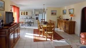 A spacious living area with a dining table, chairs, and a kitchen in the background. - Saint Palais sur Mer - BEAUTIFUL SERVICES for THIS INDIVIDUAL HOUSE (ST PALAIS SUR MER)