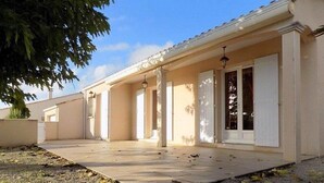 A building with a covered patio area, columns, and a door with shutters. - Saint Palais sur Mer - BEAUTIFUL SERVICES for THIS INDIVIDUAL HOUSE (ST PALAIS SUR MER)