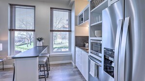 Eine moderne Küche mit Edelstahlkühlschrank, zwei Backöfen und einer Bar mit Hockern.