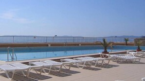 A pool area with a view of the sea, surrounded by white lounge chairs and potted plants. - Rental of a 2 rooms apartment, for up to 4 persons, in a residence with a pool, in the La... (BORMES LES MIMOSAS)