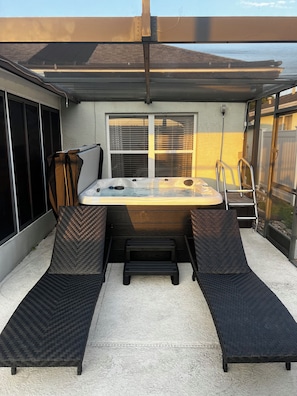 Relax in the hot tub surrounded by a sheltered patio with comfortable lounge chairs.