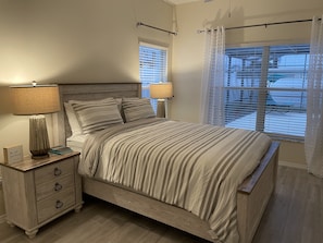 Une chambre à coucher avec un lit en bois, deux lampes de chevet, une table de chevet avec des tiroirs et une fenêtre avec des stores.