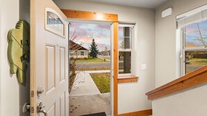 A modern entryway with a wooden door, a small window, and a view of a residential street. - Charming Home by the Park with a Hot Tub (Bozeman)