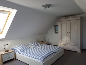 Ein Schlafzimmer mit Bett, Nachttisch, Kleiderschrank und Dachfenster.