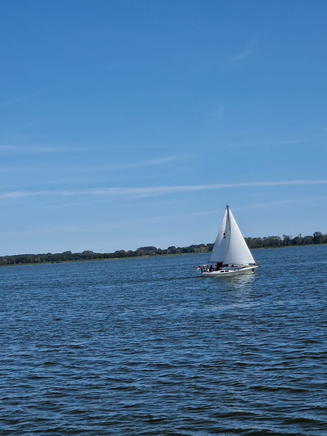 Un velero en aguas tranquilas bajo un cielo despejado.