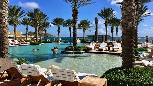 A resort pool area with lounge chairs and palm trees, overlooking the ocean. - SUITE 167m2, facing the beach, sleeps 8, DBC, sharing JW Marriot facilities. (Oyster pond)