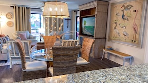 A dining area with wicker chairs, a glass table, and a hanging light fixture. - Tipsy Turtle Edgewater Villa 2901-Pickleball, Tennis, Fitness Center Included! 1st Floor-End Unit (Panama City Beach)