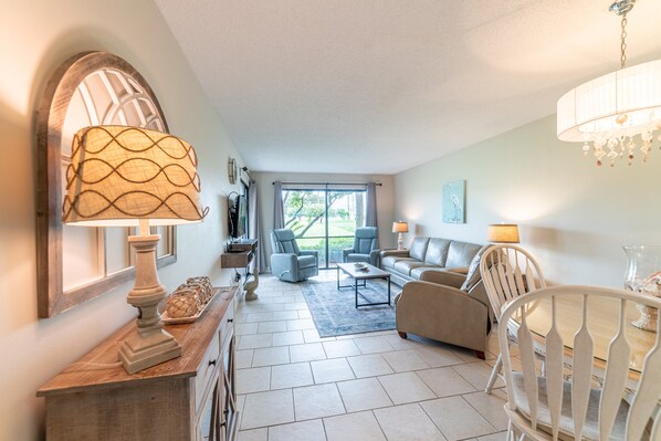 A spacious living room with a sofa, chairs, a coffee table, and a dining table.