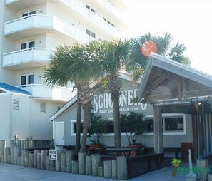 A beachfront building with a sign reading "SCHULER LAST BEACH CLUB".
