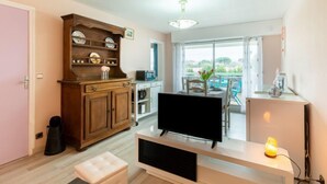 A modern living room with a flat-screen TV, wooden cabinet, and a balcony with outdoor seating. - Résidence Le Centre by Interhome (Meschers)