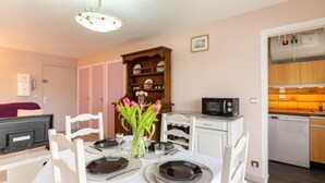 A dining area with a table set for four, a microwave, and a cabinet with dishes. - Résidence Le Centre by Interhome (Meschers)