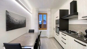 Una cocina moderna con armarios blancos, encimera de mármol y un cuadro grande en la pared.