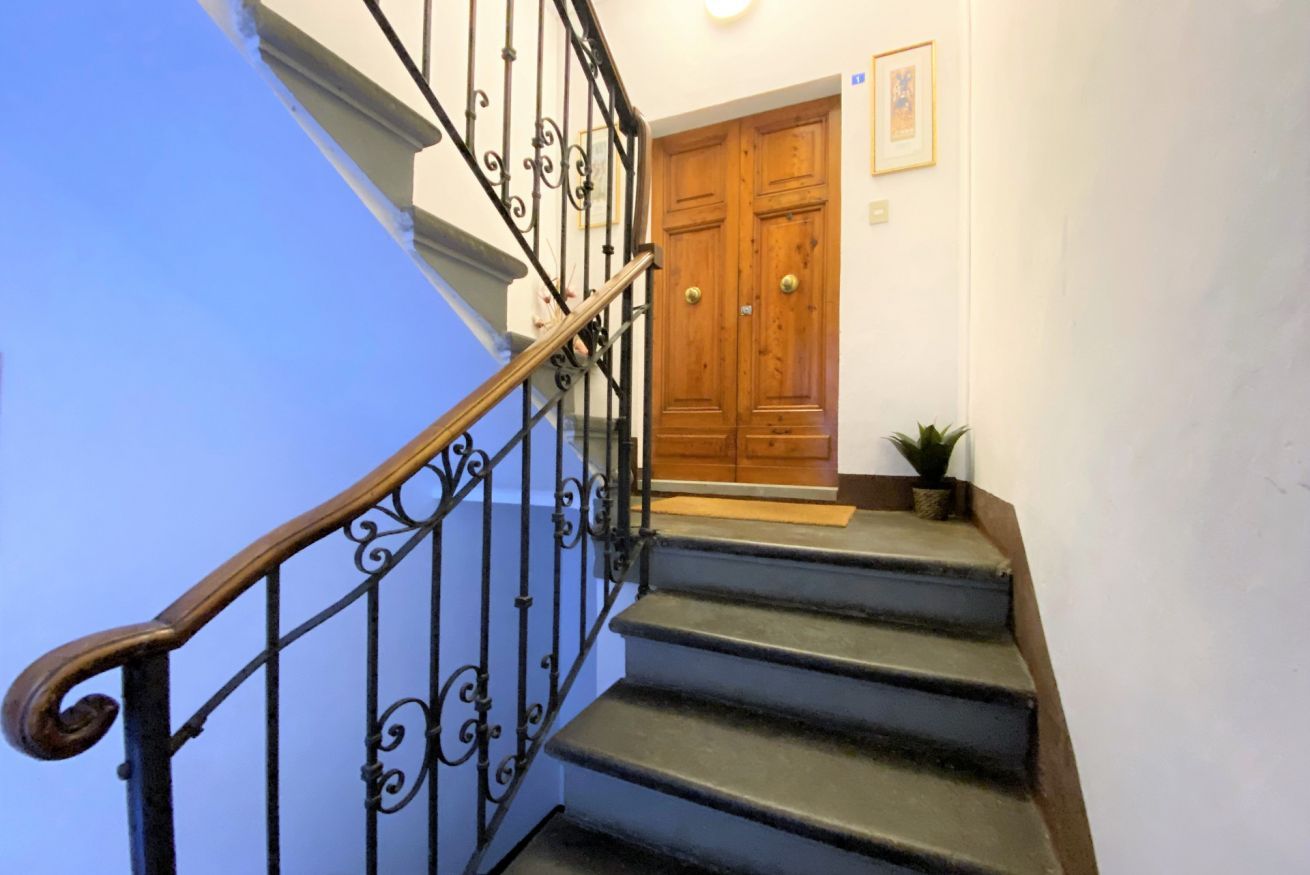 A staircase with black iron railings and wooden steps leading to a wooden door.