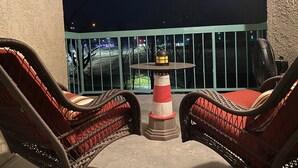 Un balcon avec des fauteuils en osier, une petite table et une décoration sur le thème d’un phare.