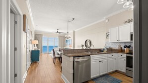 A modern kitchen with white cabinets, a granite countertop, and stainless steel appliances. - 2 Bedroom in Ocean Villa Resort - Stunning views and all the comforts of home! (Panama City Beach)