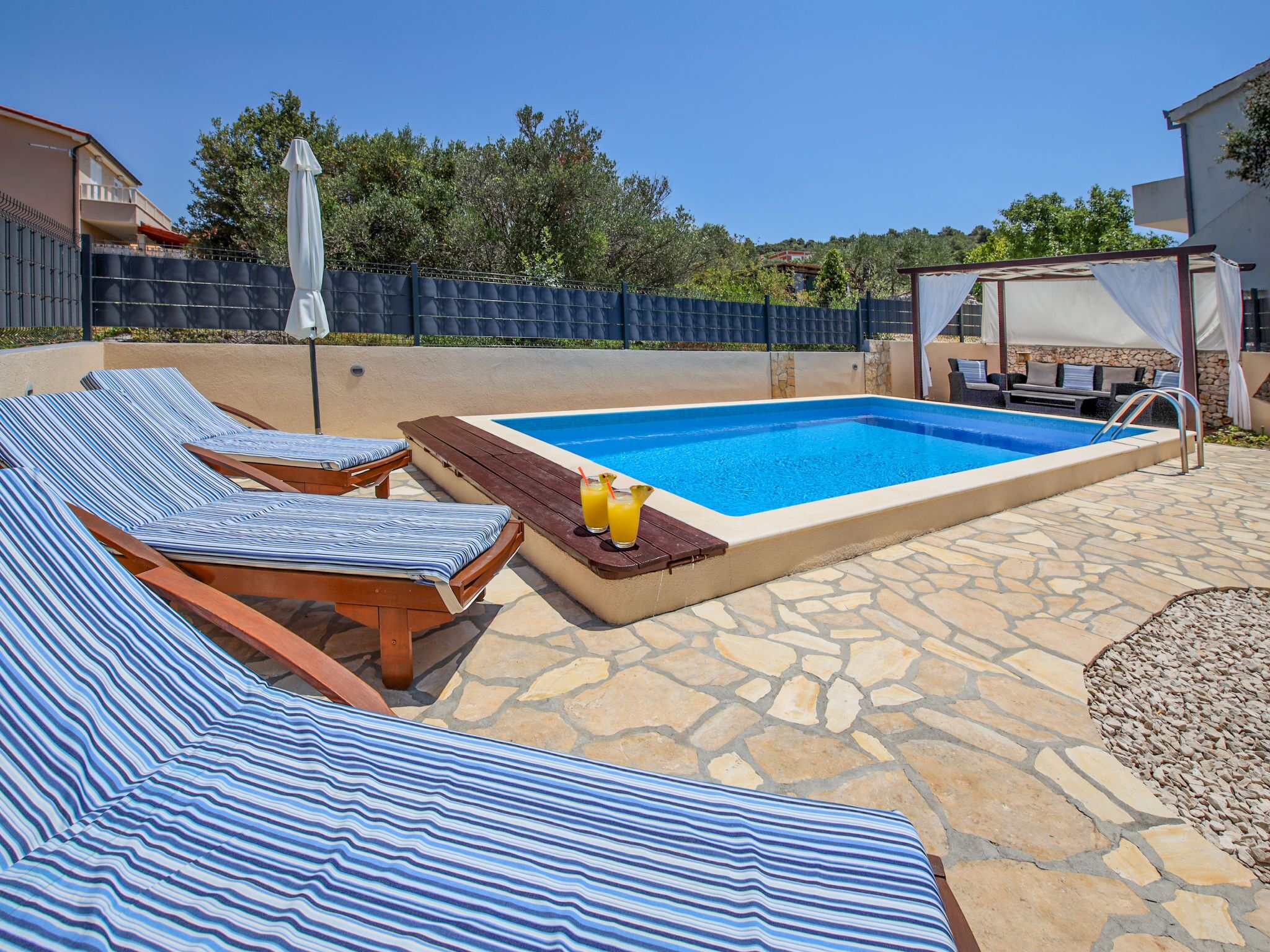 Une piscine avec des chaises longues et une table où sont servis des boissons.
