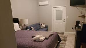 Un dormitorio con cama, sofá, televisor y cafetera.