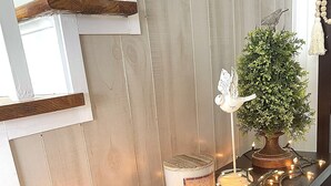 Ein gemütliches Interieur mit einem Holztisch, der mit einer Kerze, einem kleinen Topfpflanzen und einem dekorativen Schild geschmückt ist.