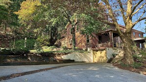 Ein traditionelles Backsteinhhaus mit Veranda, umgeben von Bäumen und einer kleinen Steinbrücke.