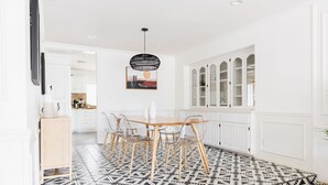 Una cocina moderna con armarios blancos, una mesa de comedor de madera y sillas transparentes.