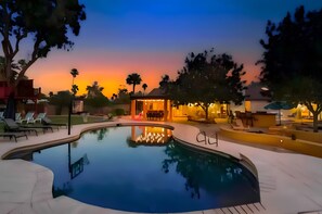 A swimming pool with lounge chairs and a covered seating area, surrounded by trees and a sunset in the background. - Amazing Scottsdale Luxury - Heated Pool, Hot Tub (Scottsdale)