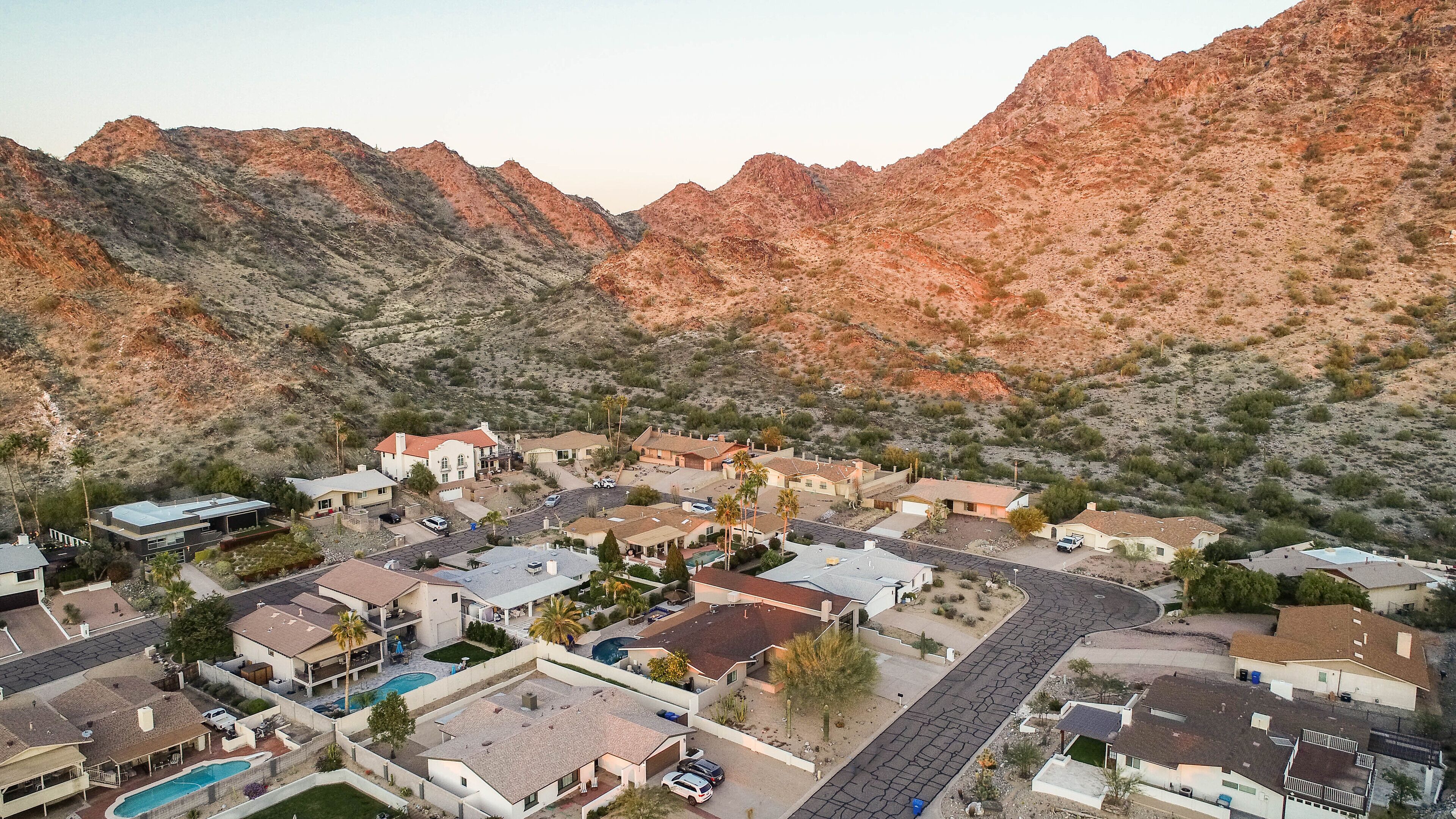 A residential area with houses, a swimming pool, and a mountain backdrop.
