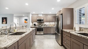 A modern kitchen with granite countertops, stainless steel appliances, and neutral-toned cabinetry. - Biltmore Highlands by Porter | Luxury Home w/Private Pool and Mountain Views (Phoenix)