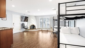 A modern room with a bunk bed, wooden flooring, a fireplace, and a TV mounted on the wall. - Biltmore Highlands by Porter | Luxury Home w/Private Pool and Mountain Views (Phoenix)