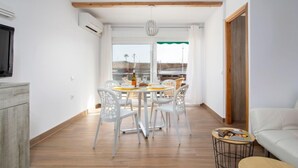 Uma sala de estar moderna com área de jantar, um sofá e uma mesinha de centro com revistas.