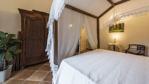 Un dormitorio con una cama, un armario de madera, una mesita de noche con una lámpara y una silla.