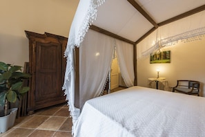 Une chambre à coucher avec un lit, une armoire en bois, une petite table avec une lampe et une chaise.