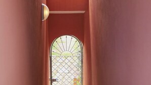 A narrow hallway with a door featuring a metal gate and a light fixture on the wall. - La Ginestra Three-room apartment sleeps 6 (San Teodoro)