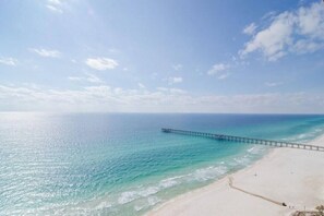 A beach with a pier extending into the ocean.