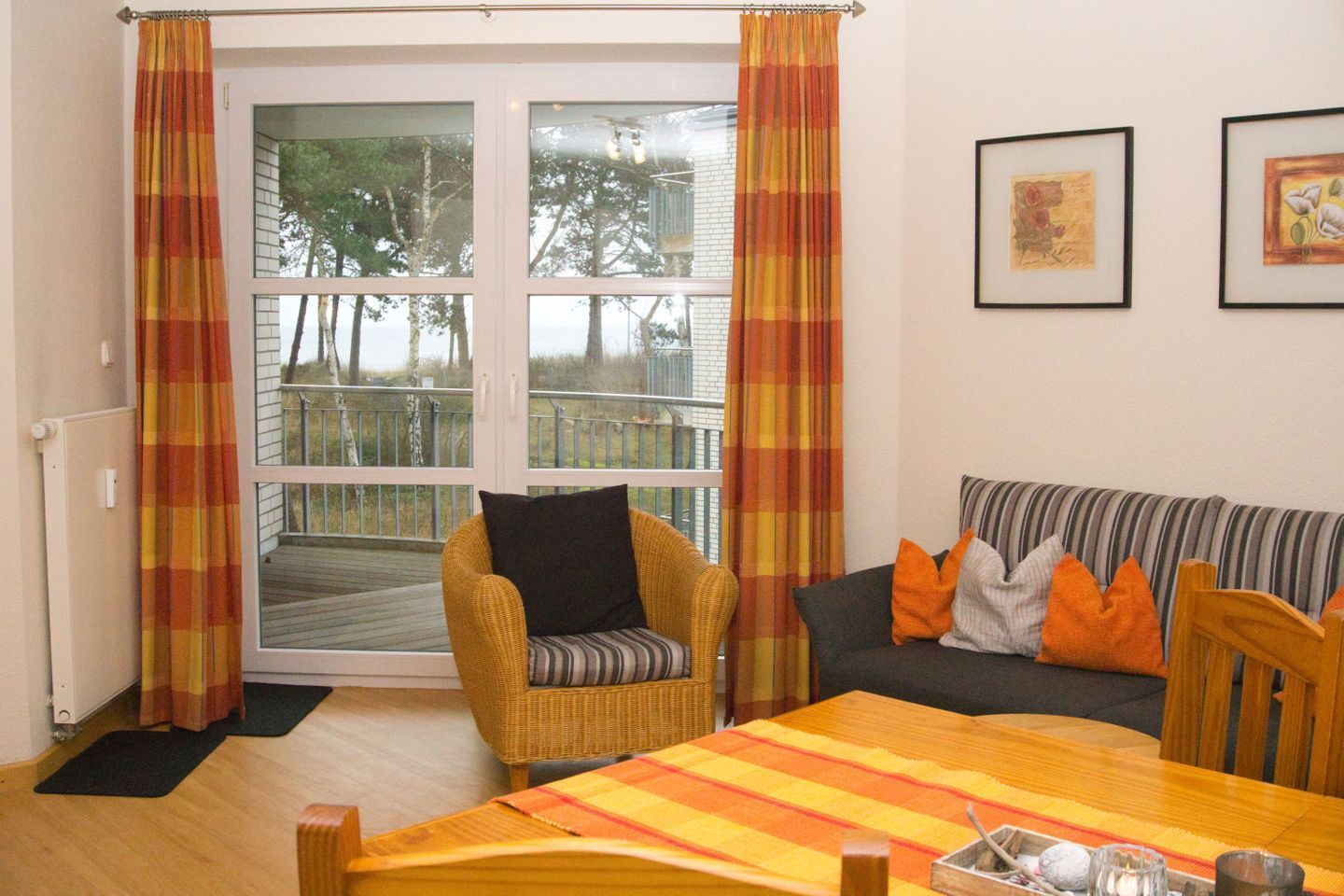 A cozy living room with a wicker chair, a striped sofa, and a wooden dining table.