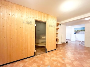 Une pièce en bois avec une porte donnant sur une salle de bain, un sol carrelé et un tableau accroché au mur.