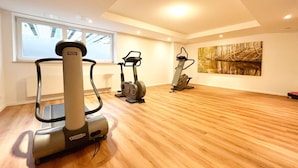 A spacious room with a large window, a treadmill, an elliptical, and a stationary bike. - Dünenresidenz - Apartment directly on the beach, balcony with sea view - Dünenresidenz FeWo (Breege)