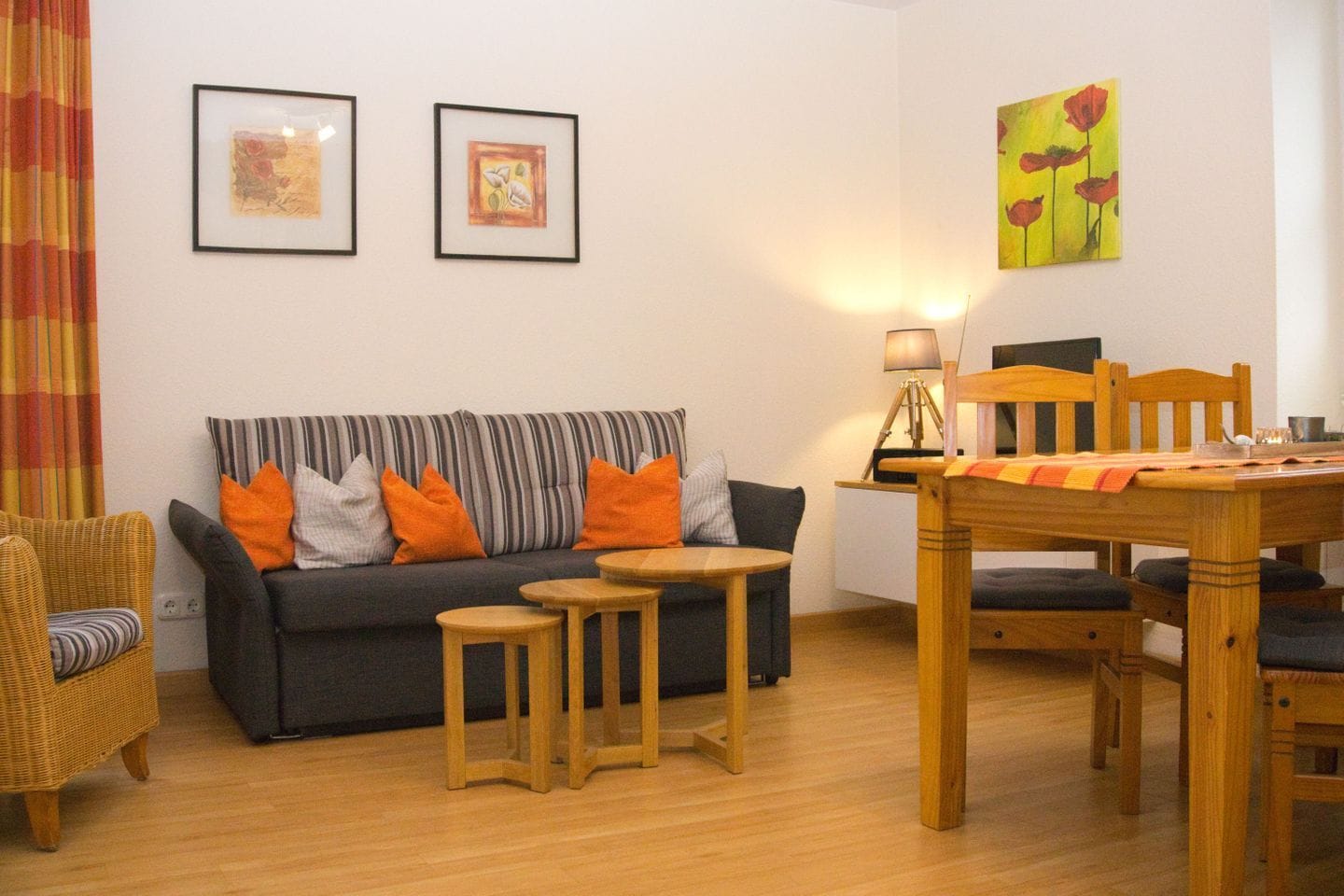 Un salon comprenant un canapé, deux tables d’appoint, une table à manger avec des chaises, une lampe et deux œuvres d’art encadrées accrochées au mur.